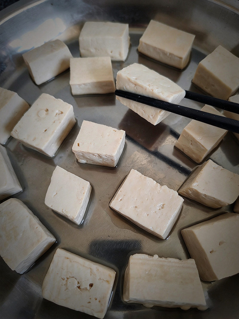 Arranging inoculated tofu cubes neatly on a tray for fermentation