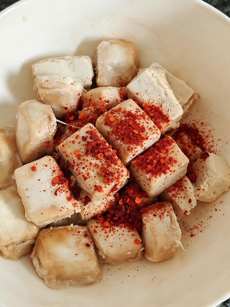 Adding chili powder, salt, and spices into a mixing bowl