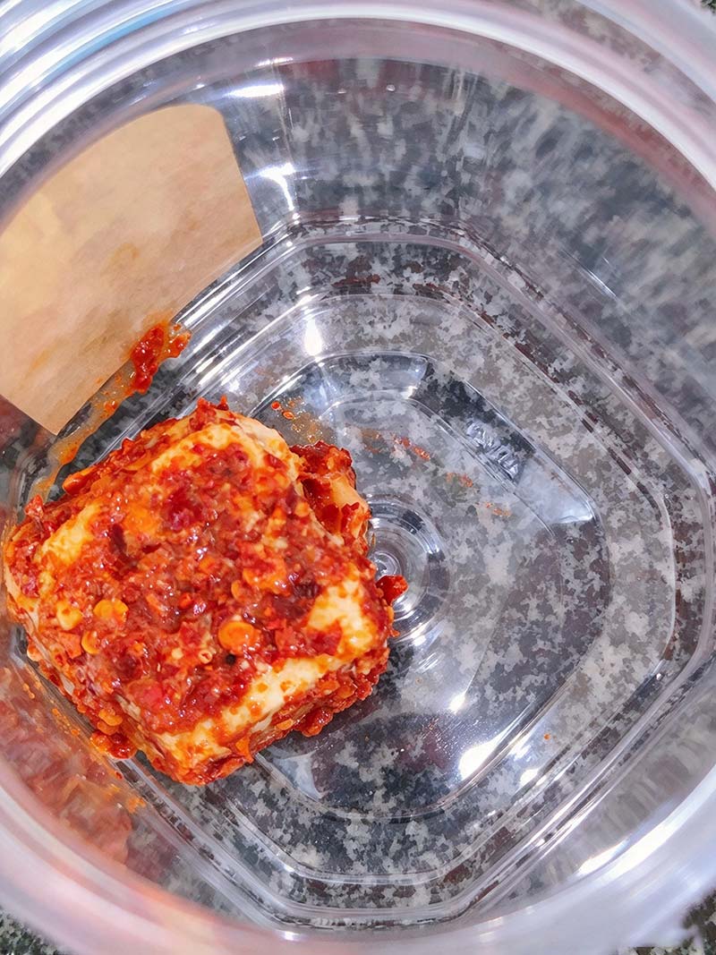 Packing spice-coated hairy tofu cubes neatly into a clean glass jar