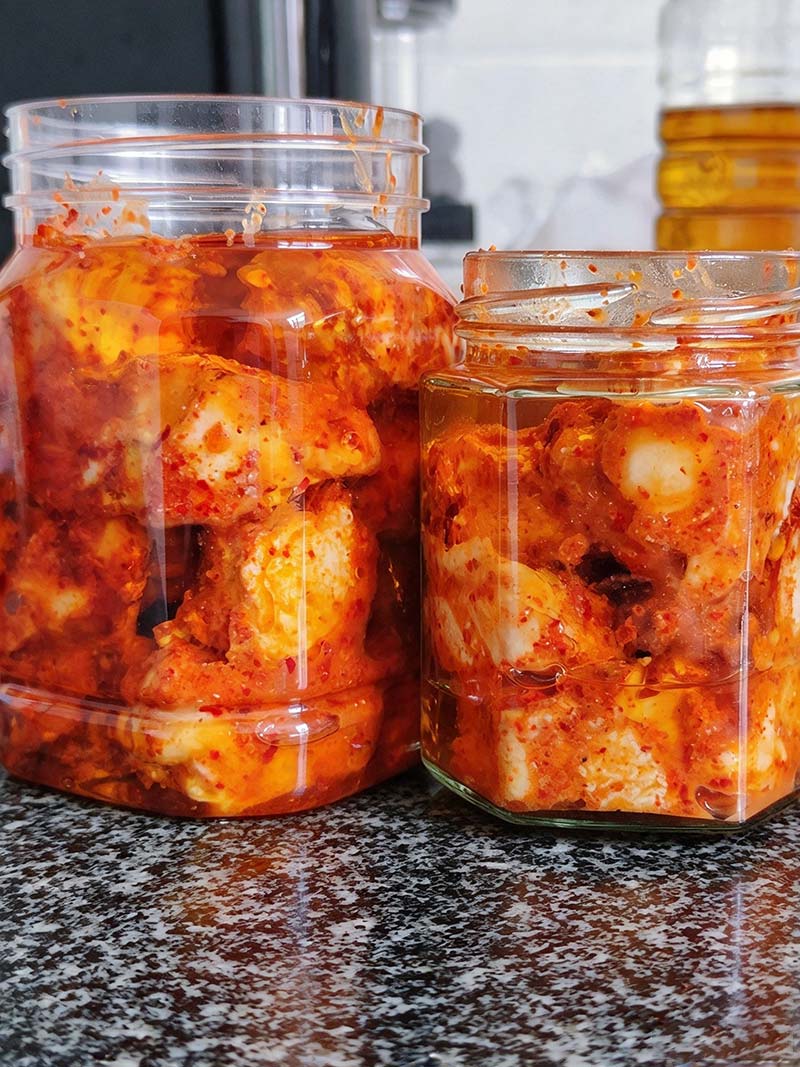 Spice-coated hairy tofu completely submerged in oil inside a glass jar for oil immersion